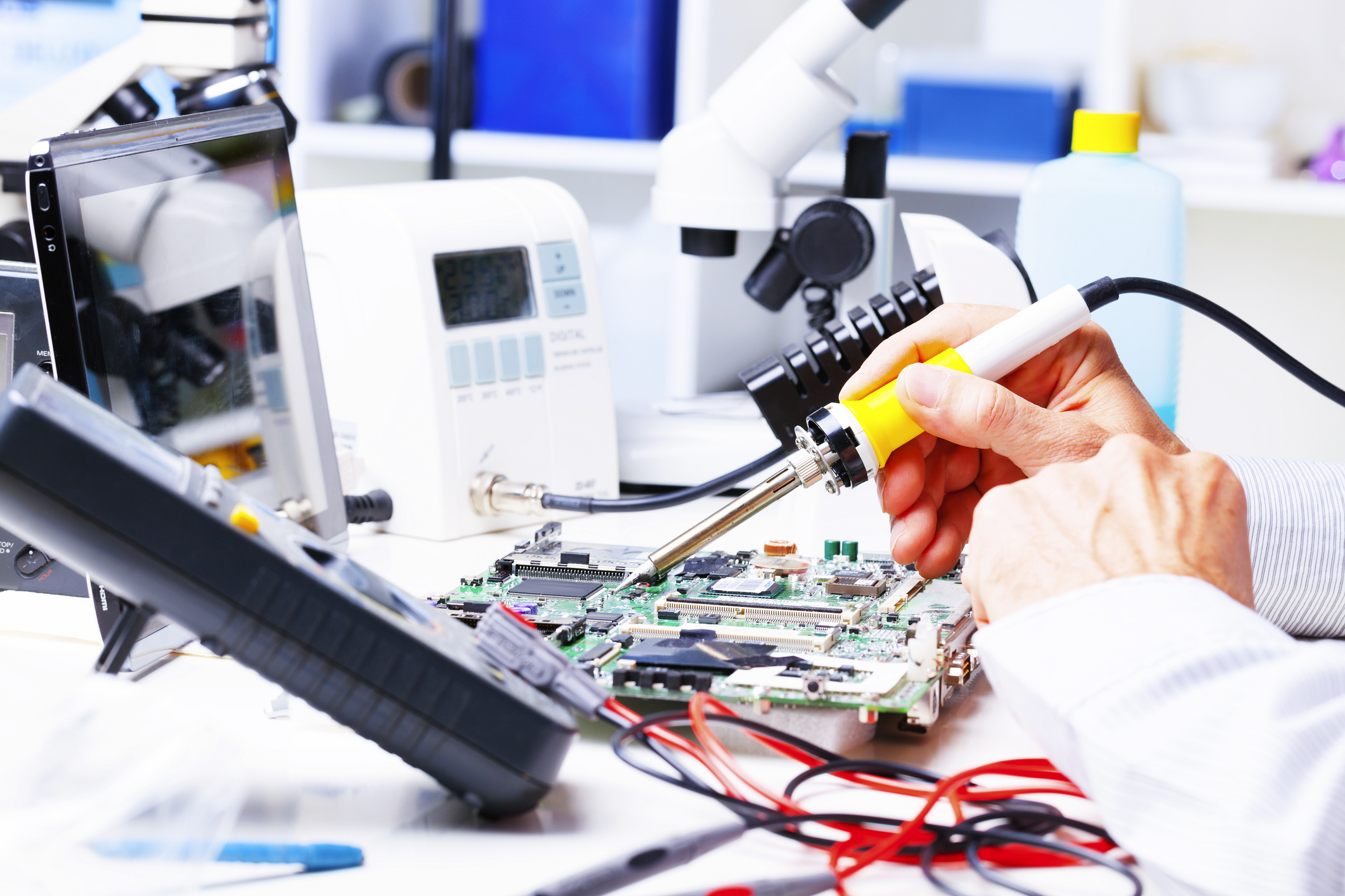 Person using soldering equipment to repair a circuit board.